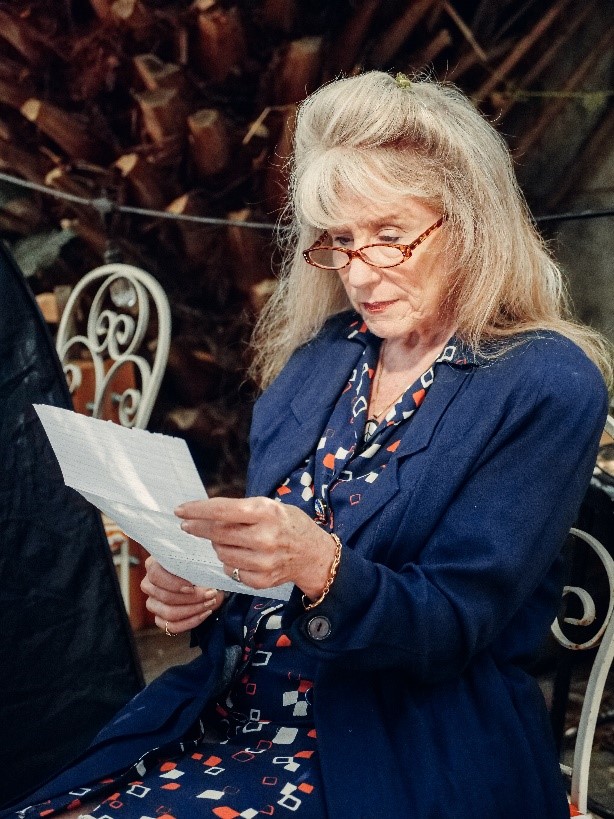 IMAGE 2: Woman in blue coat holding white paper