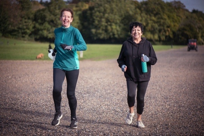 Two older adults jogging in a park