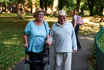 Two older adults walking side by side in a park